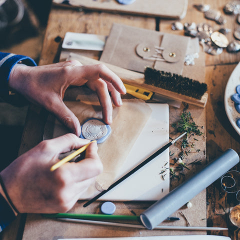 woman sitting at bench making clay jewellery