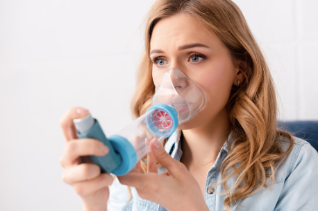 woman using an asthma inhaler.