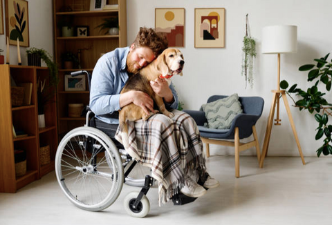 A young man in a wheelchair with his puppy on his lap.