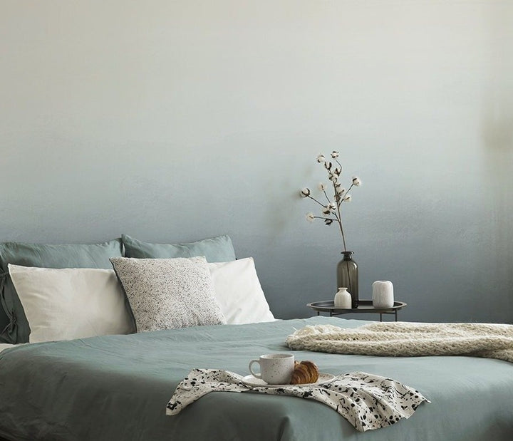 Blue bedroom with blue bedsheets and an gradient coloured wallpaper