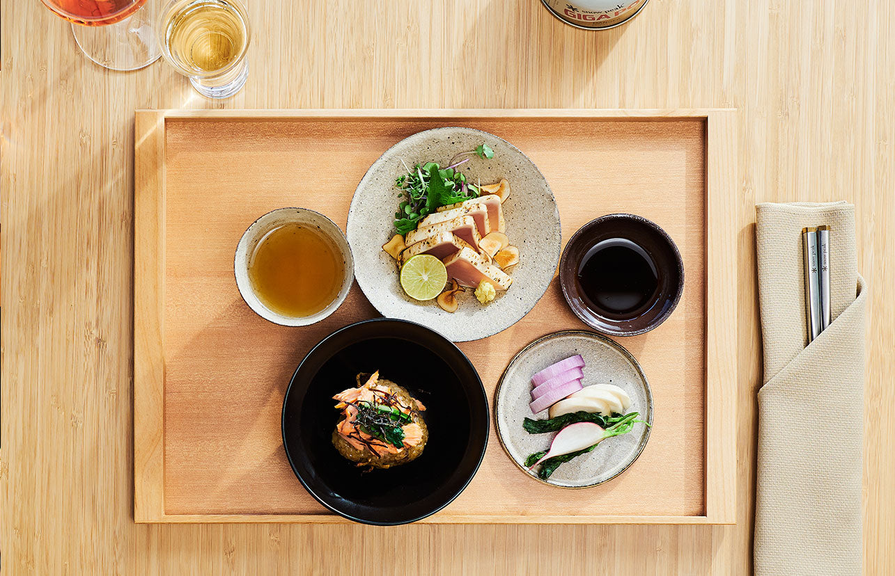 A beautiful wood tray filled with small plates of perfectly plated food.