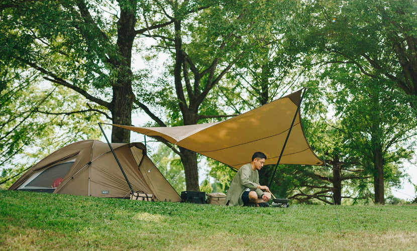 Snow Peak tent and tarp combination set in the woods, showing the beautiful clean lines of the design that complement the sunny forest.