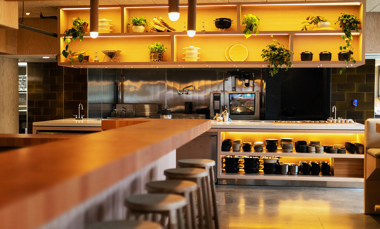 Image of the open kitchen, faced with open shelving displaying plateware, plants, and Snow Peak gear.