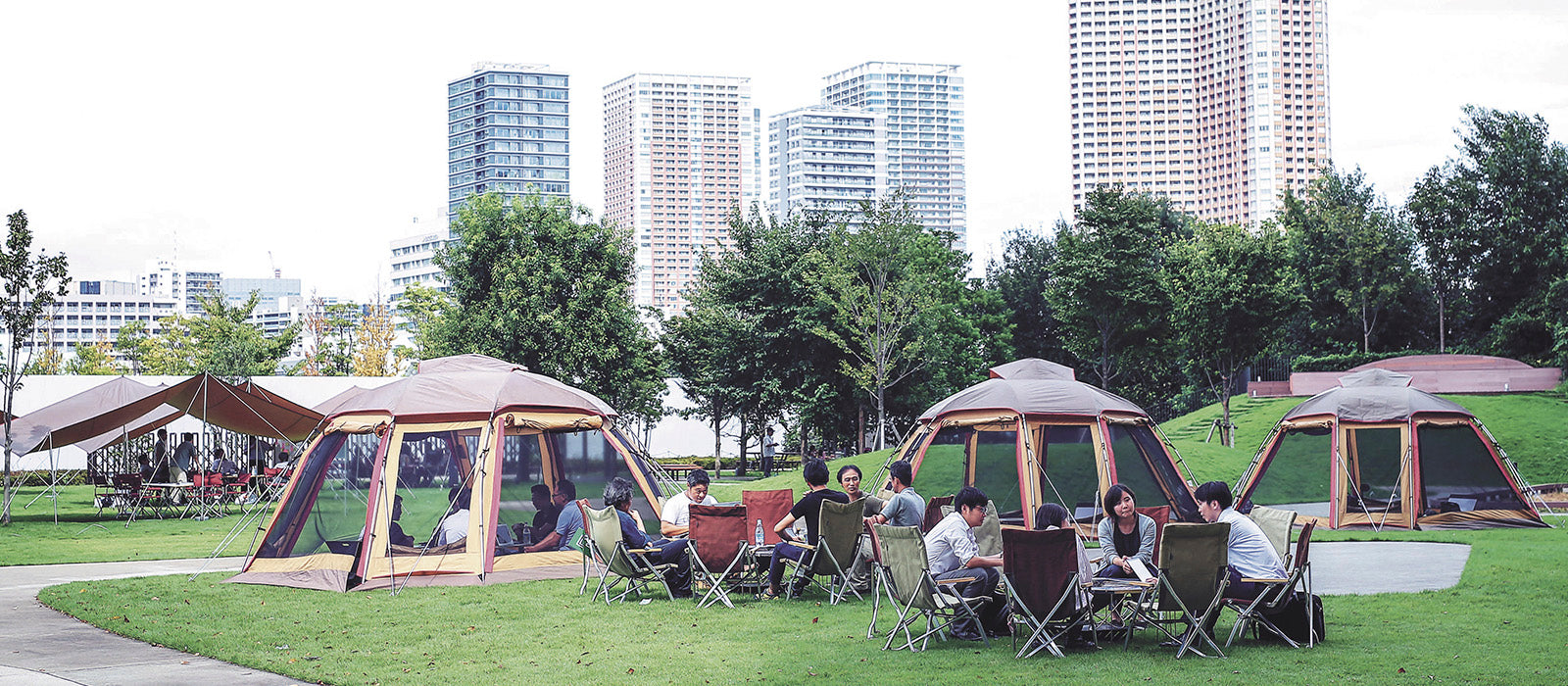 Image of campers on a campfield in front of urban setting