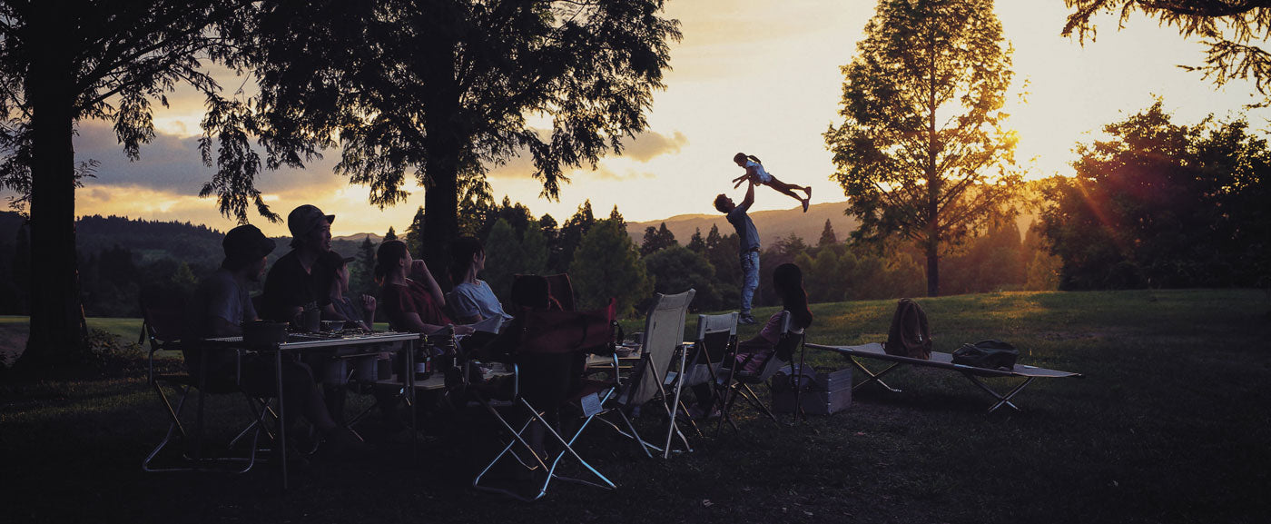 a group of campers standing around. A father holding his child in the air.