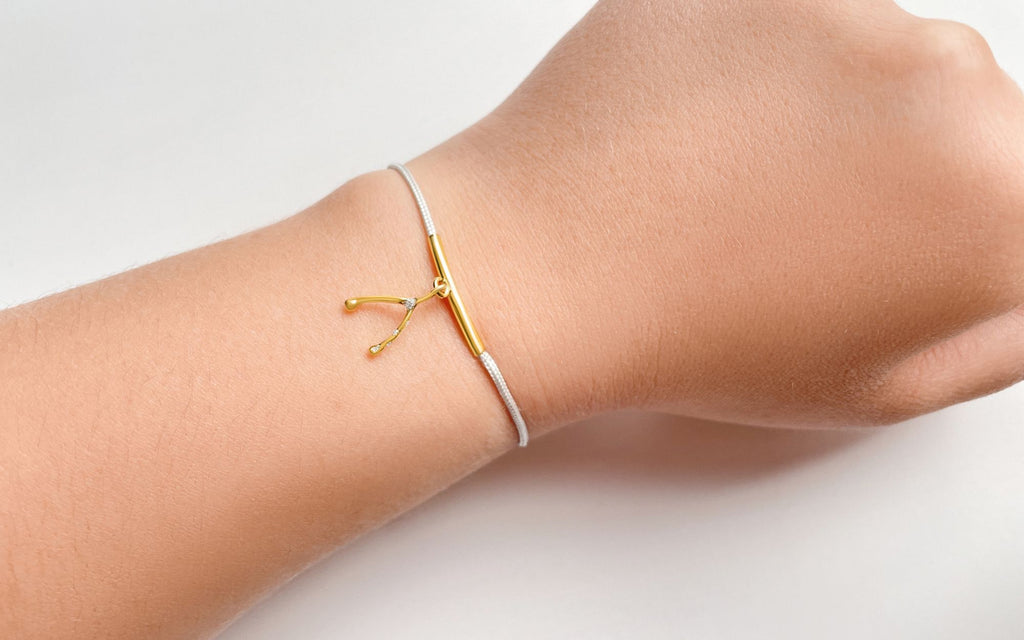 An arm on a white background with the Wishbone String Bracelet on the wrist.