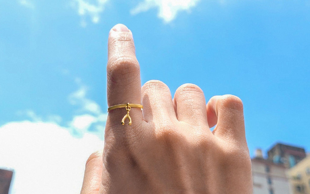 A hand with a wishbone ring raised into the sky