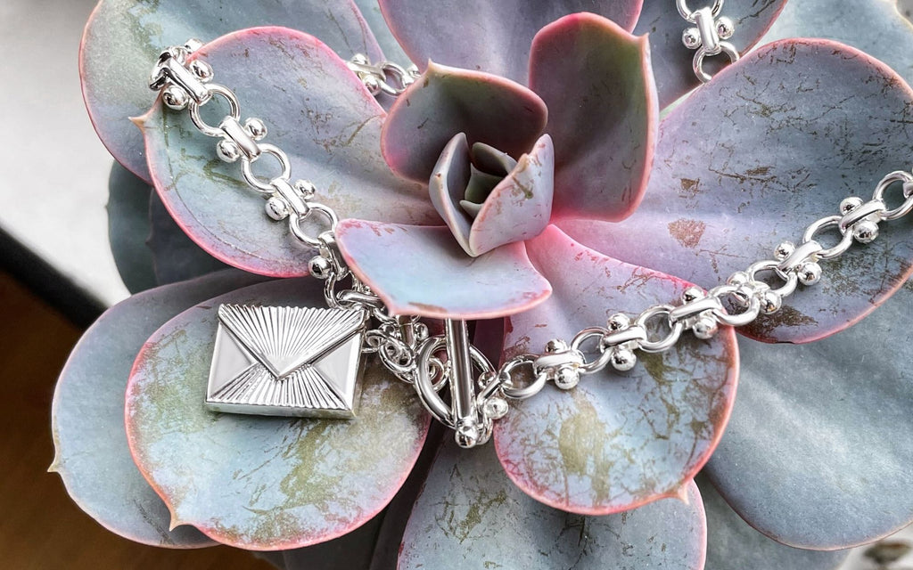 Love letter envelope locket on top of a succulent.