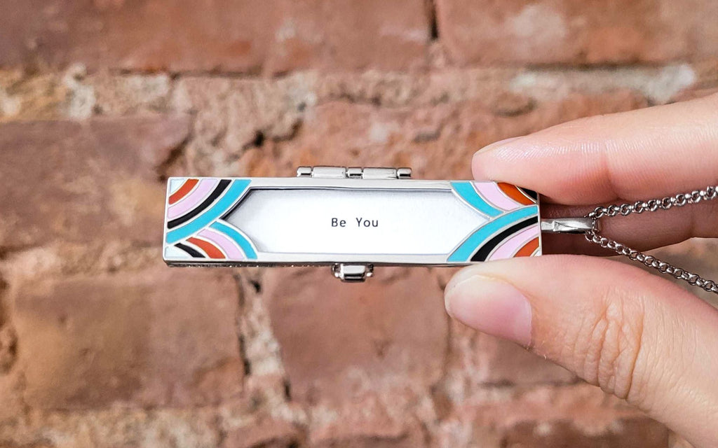 Fortune locket held in front of a brick background with the fortune "Be You"
