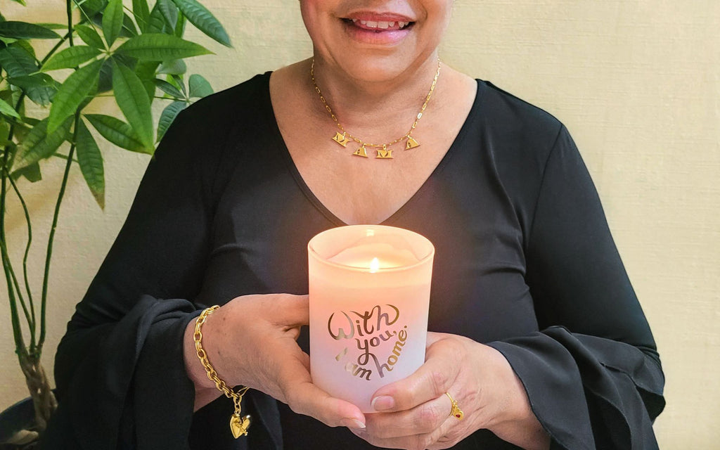  Woman holding a Secret Fortune Candle and wearing the Mama Letter Necklace in gold.