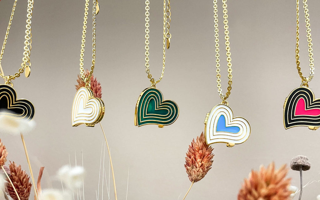 Five deco heart lockets hanging over a few flowers.