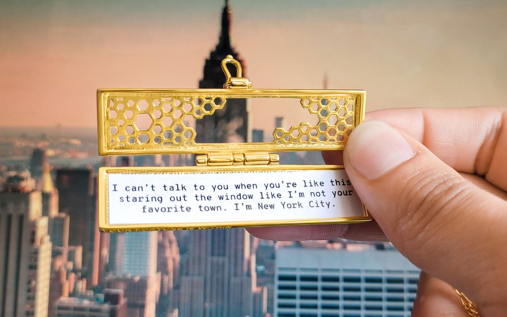 Honeycomb fortune locket being held in front of a New York City skyline.