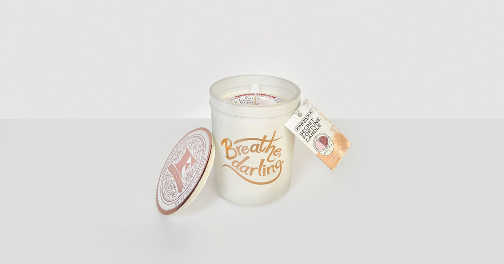 The "Breathe, darling." Secret Fortune Candle shown with its lid and gift tag.