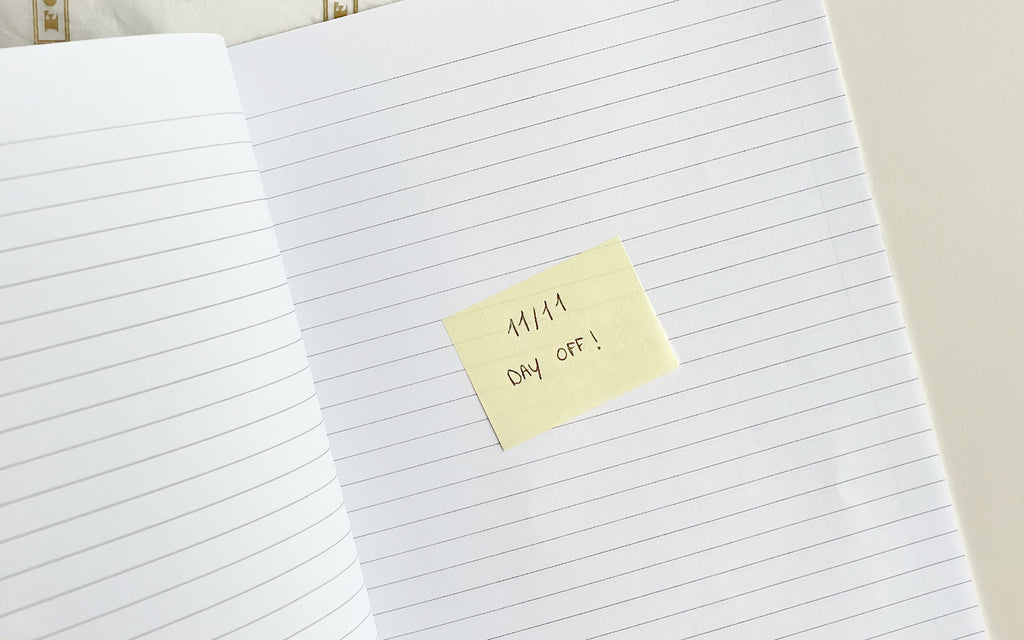 A notebook with a post-it note that reads "11/11 Day Off!" 