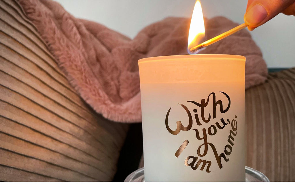 Candle being lit with a match, with a couch and blanket in the background.