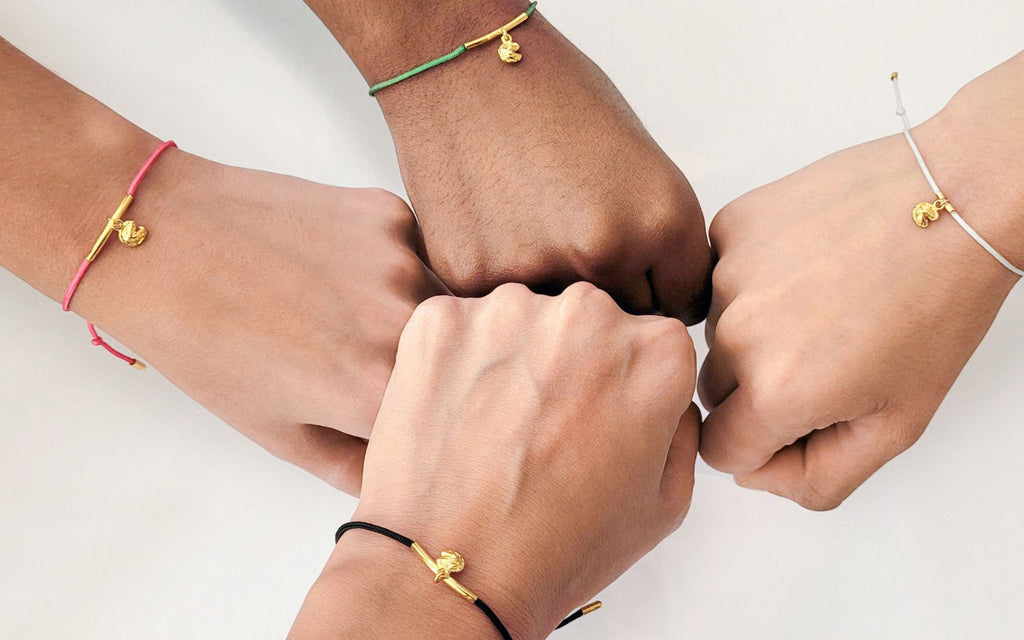 Fist bumps with fortune cookie string bracelets being worn.