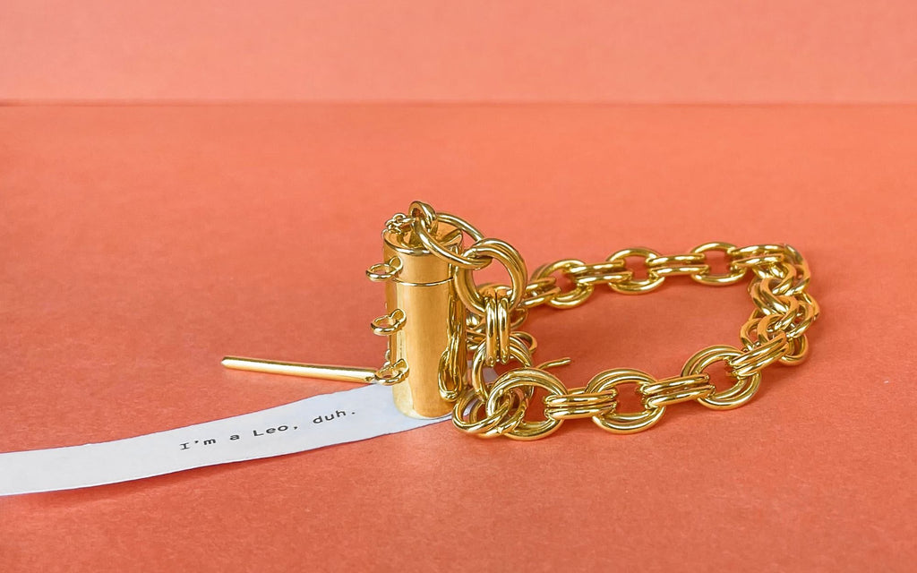 Capsule + Wand bracelet with a fortune over a slight orange background.