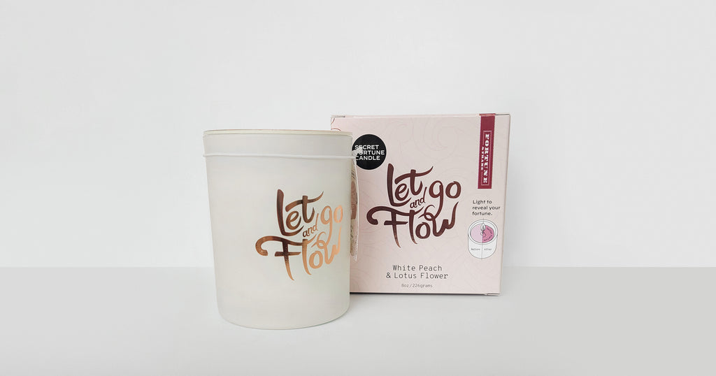 The "Let go and flow." Secret Fortune Candle shown with it's box packaging.