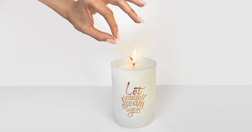 The "Let yourself dream again." Secret Fortune Candle being lit by a hand.