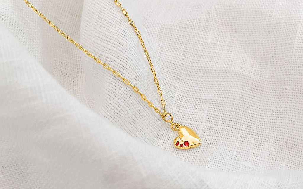 Jeweled heart pendant over a white cloth.