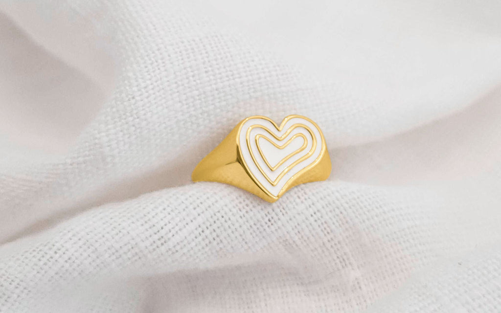 Ivory and gold heart ring tucked into a white cloth.