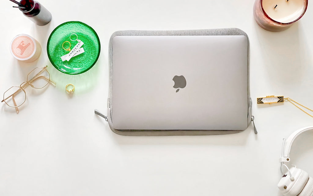 A laptop, Deco Fortune Locket (onyx), glasses, candle, water bottle, and green bowl containing two fortunes and a gold jeweled heart charm ring and silver fortune cookie charm ring.