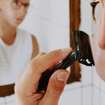 man using closed comb safety razor