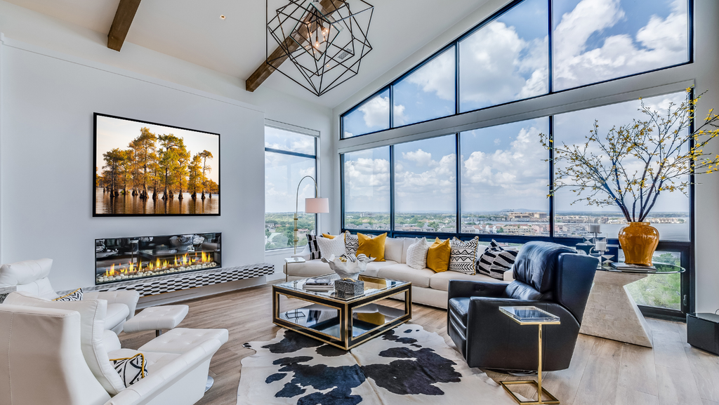 luxurious black white and gold room with a large print above the fireplace of golden trees in a black frame