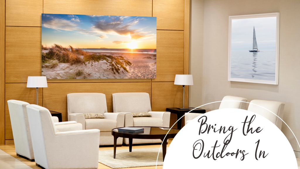 landscape artwork of beach dunes and a sunset ocean with a sailboat photograph decorating a hotel lobby