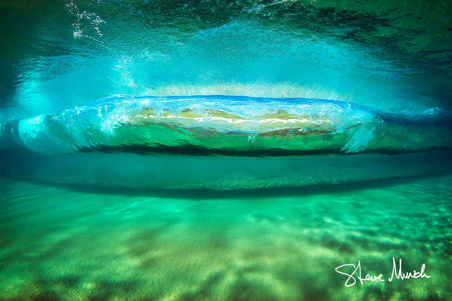 Wave art photography taken underwater beneath a giant green wave reaching the shore.