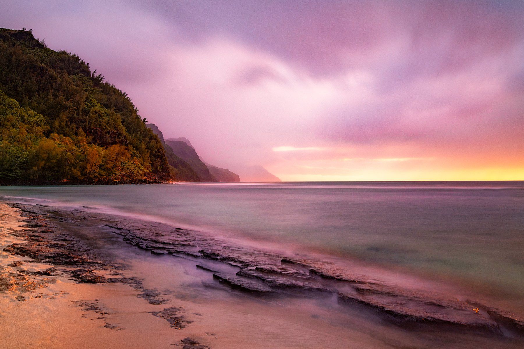 Beautiful beach sunset photography of Ke'e Beach and the ocean bathed in pastel tones.