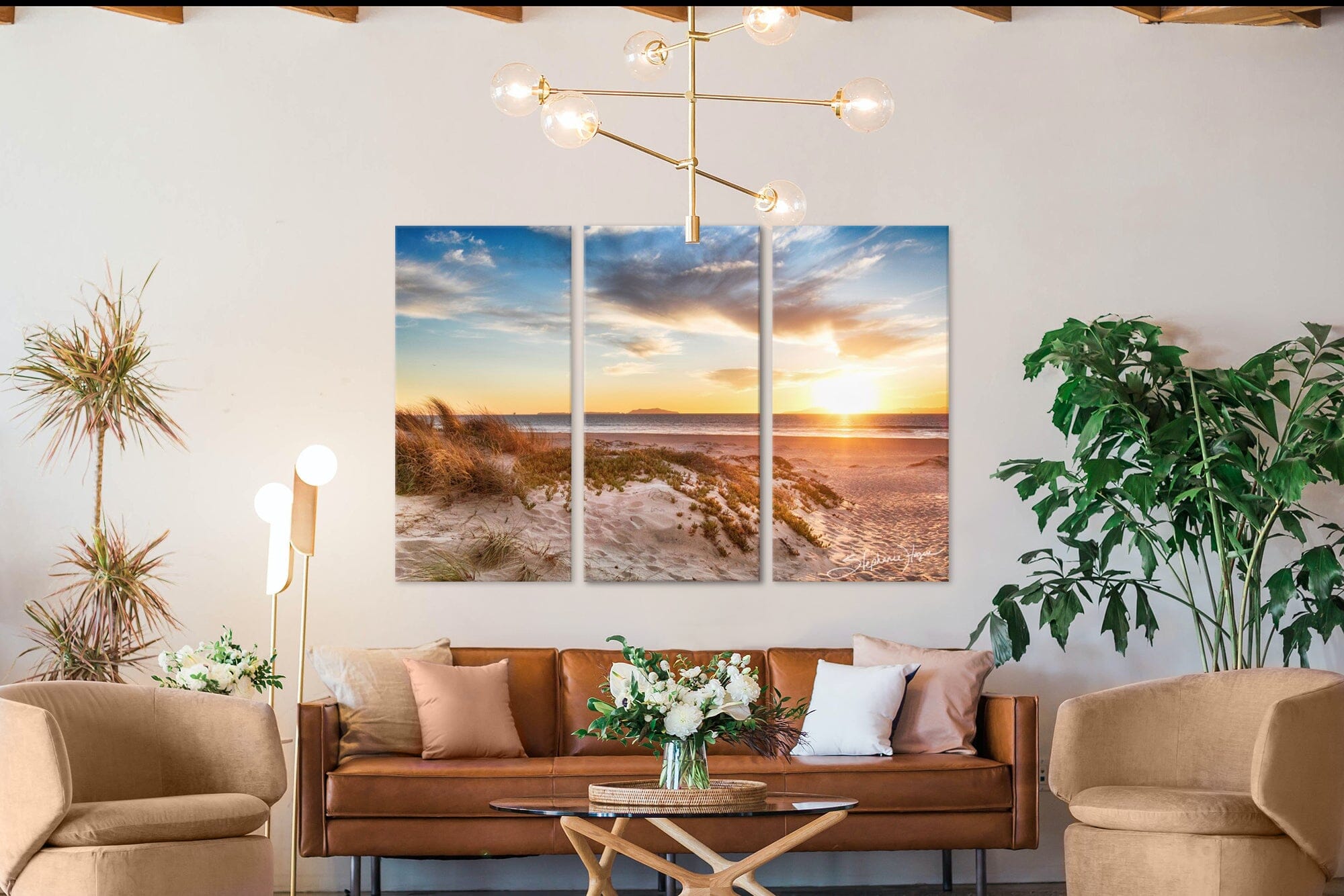 Beach sunset photography wall art of a setting sun over the ocean. Wall art is in a sitting room scene.