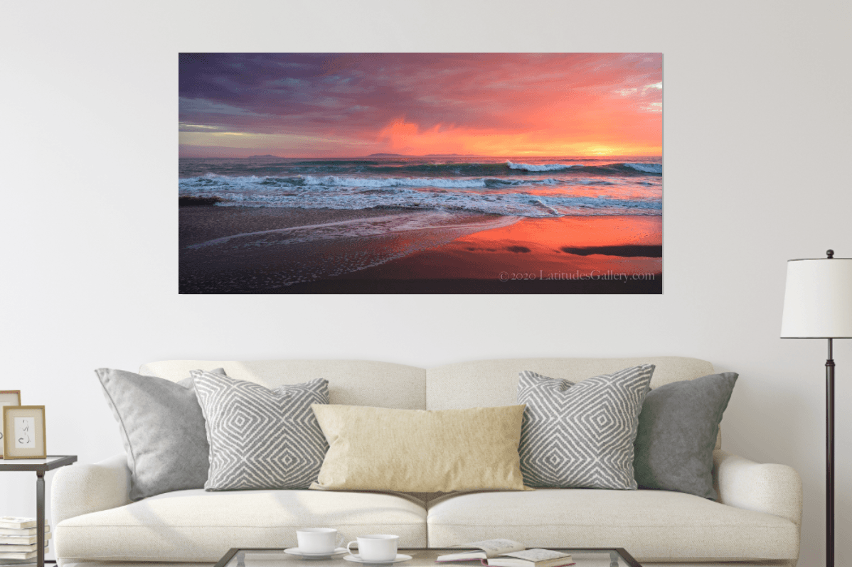 A dramatic orange, pink, purple, and red sunset wall art piece featured in a room scene.