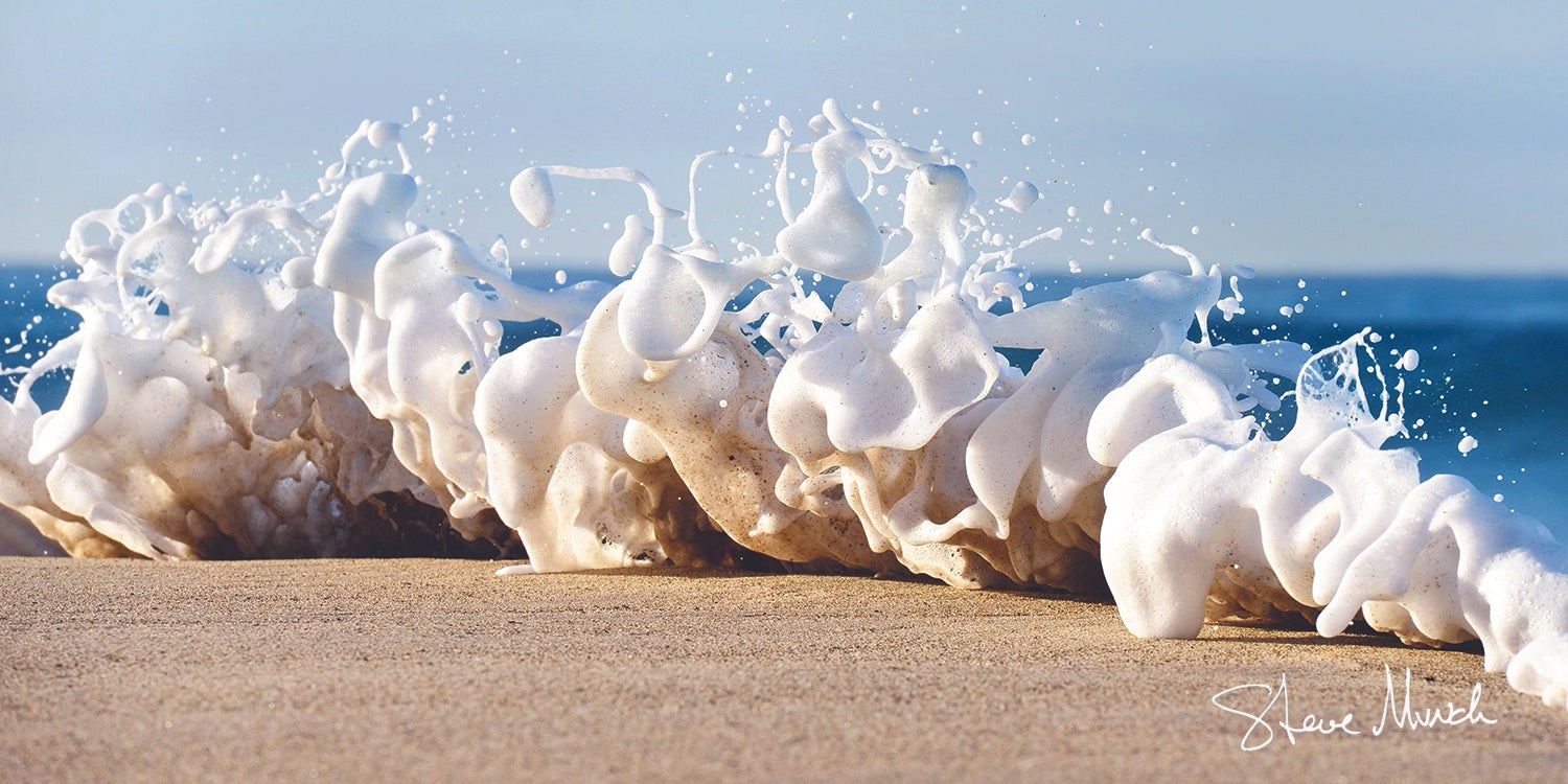 Coastal artwork of a fresh foam wave dancing playfully on a sandy beach.