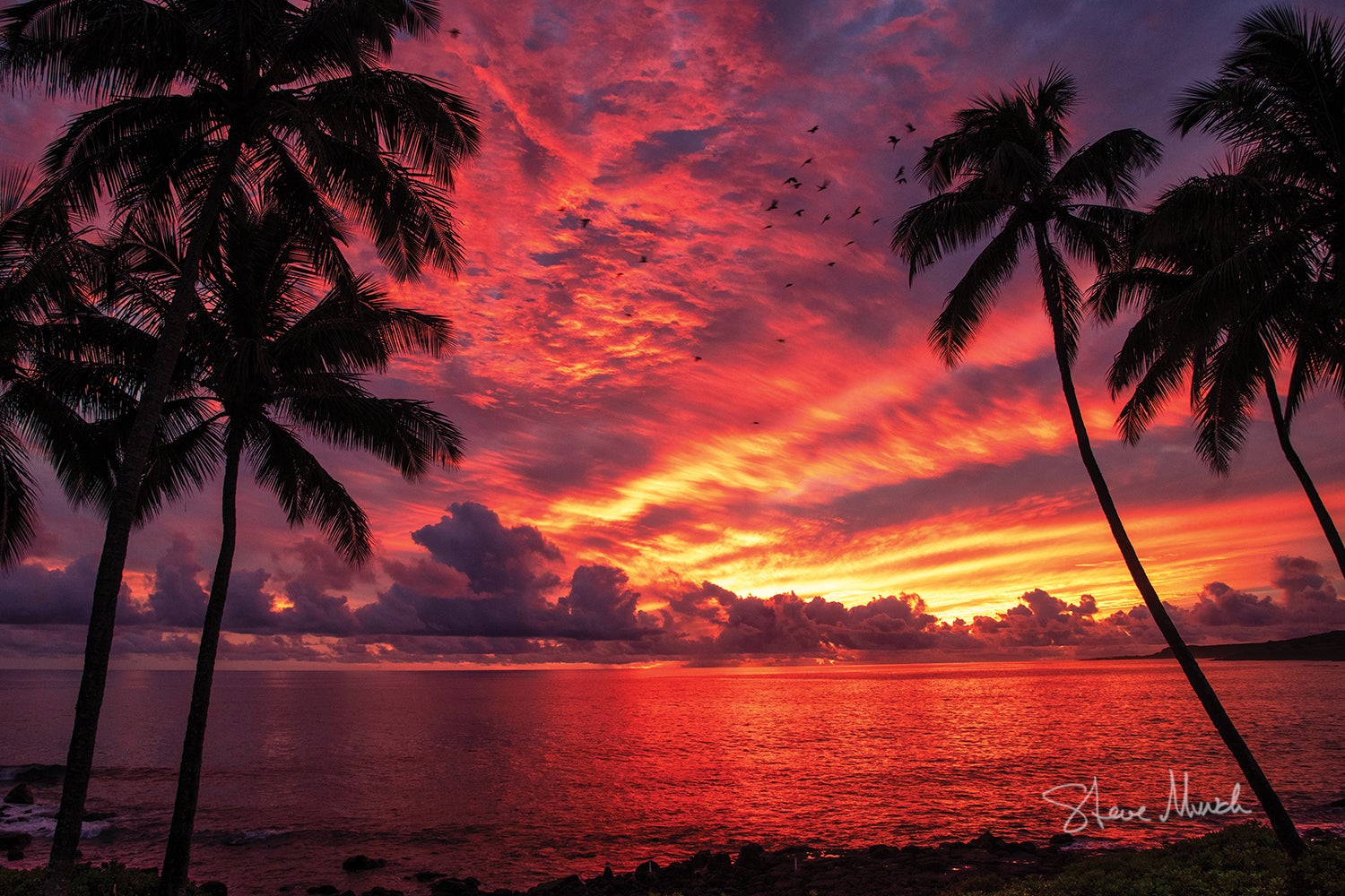 Kauai photography of a fire red sunset over the ocean.