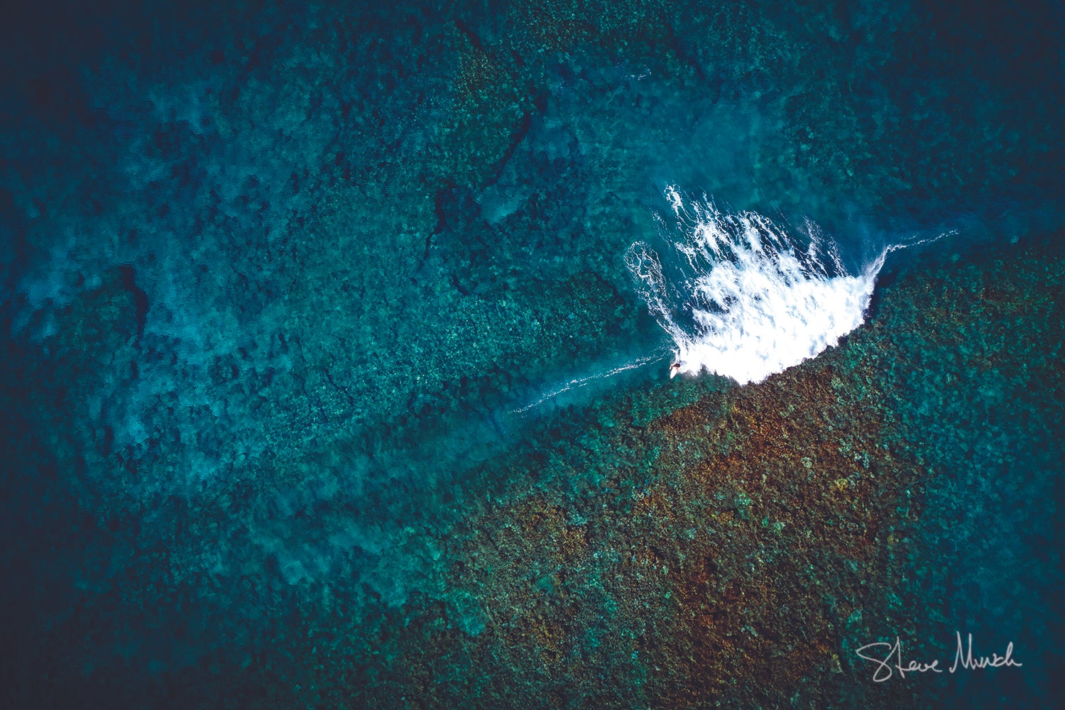 Coastal artwork of an aerial view of ultra-clear blue waters over a reef as a lone surfer catches a wave in Hawaii.