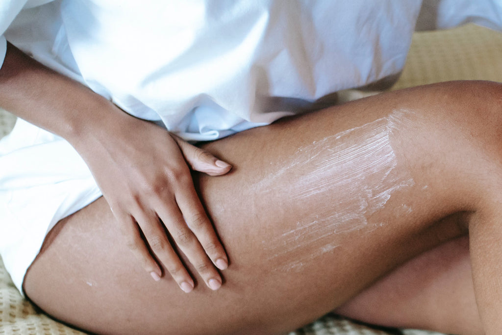 A woman moisturizing her legs and showing the role of essential oils in enhancing body butter benefits