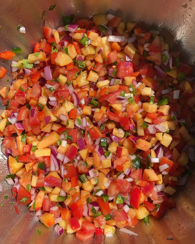 Close up of fresh peach salsa in a metal mixing bowl.
