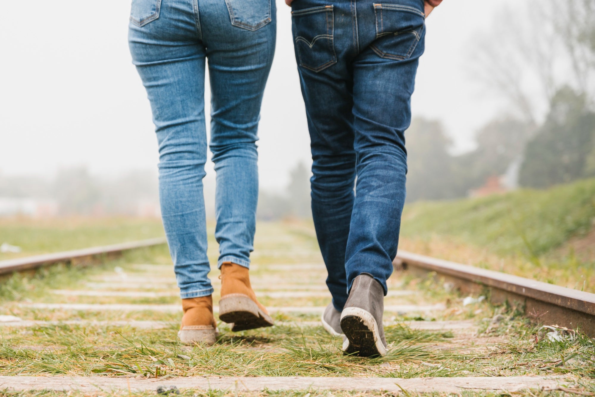 young-couple-walking-along-tracks-together