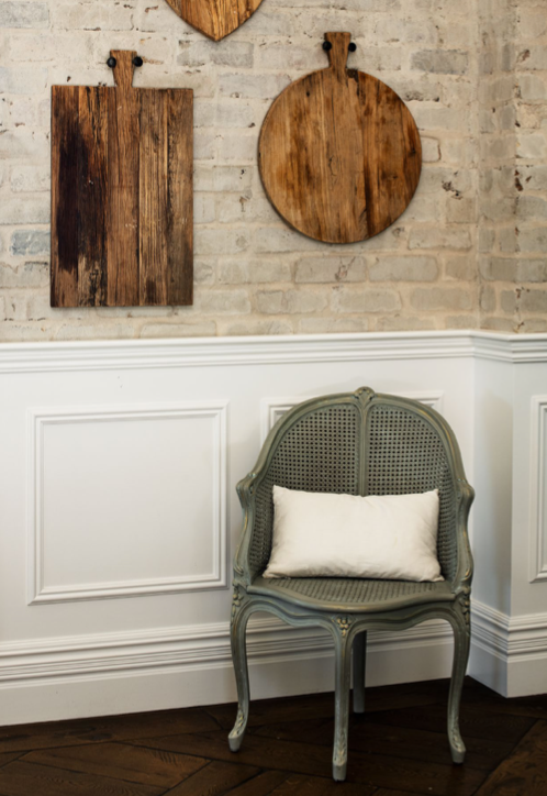In the living room, a Dusty Luxe chair contrasts with the wainscoting and bagged brick walls.