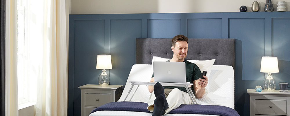 a man working on his laptop in an adjustable bed