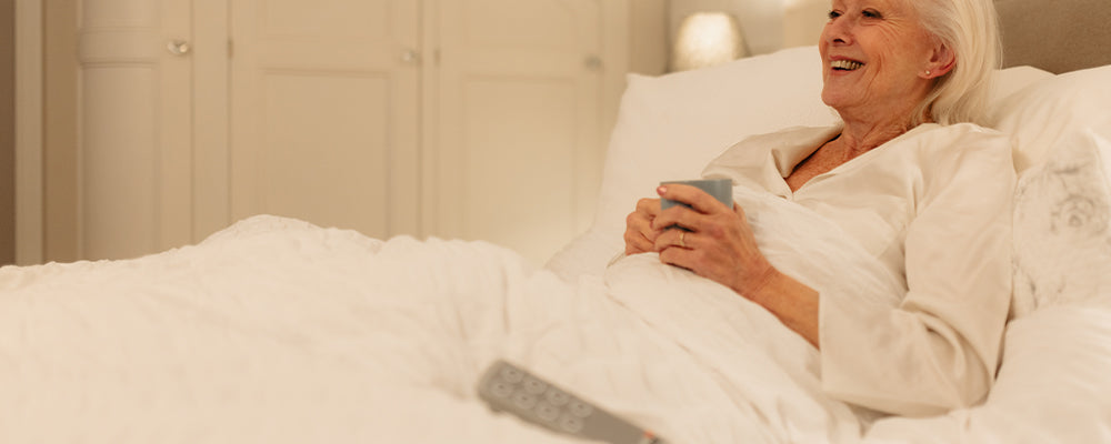 a lady laying in a profiling bed with the remote