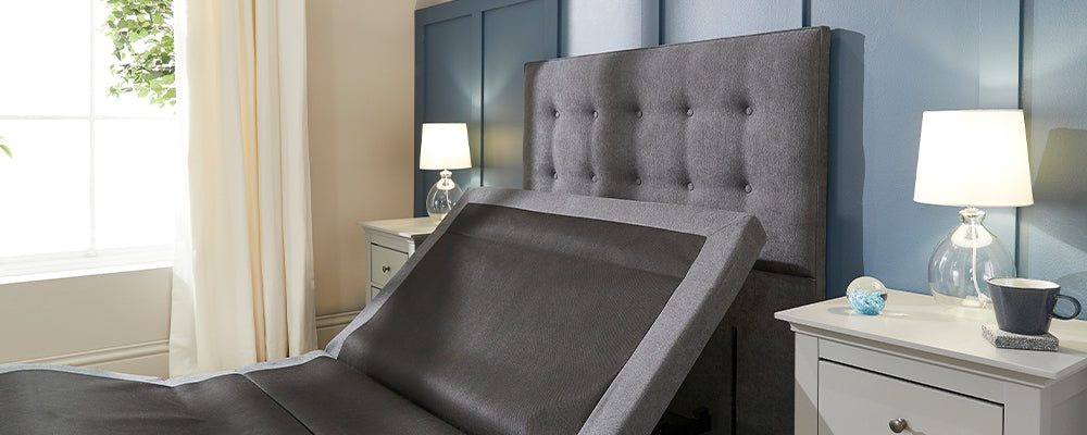 An adjustable bed with a grey button square headboard attached to it