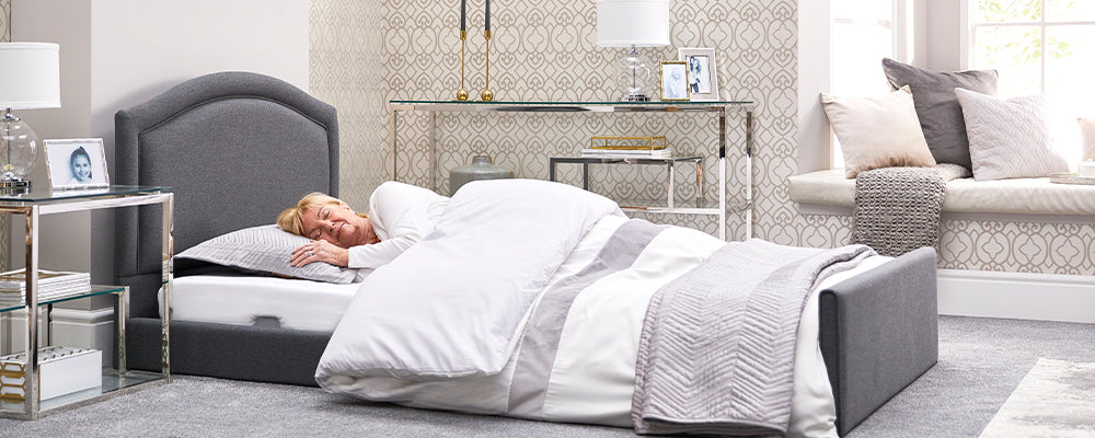 Elderly woman sleeping in a grey profling bed that is close to the floor