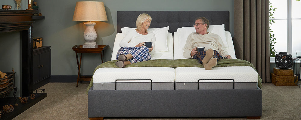 An elderly couple sat upright in a dual adjustable bed