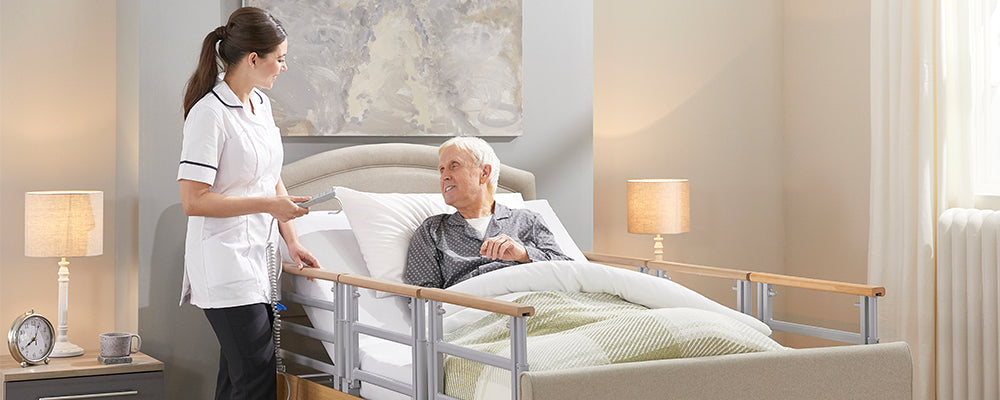 a carer with the elderly man in bed with the side rails up