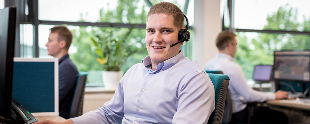 A young salesman wearing a headset smiling