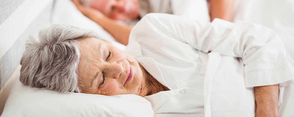 Older woman laid on her side in bed sleeping