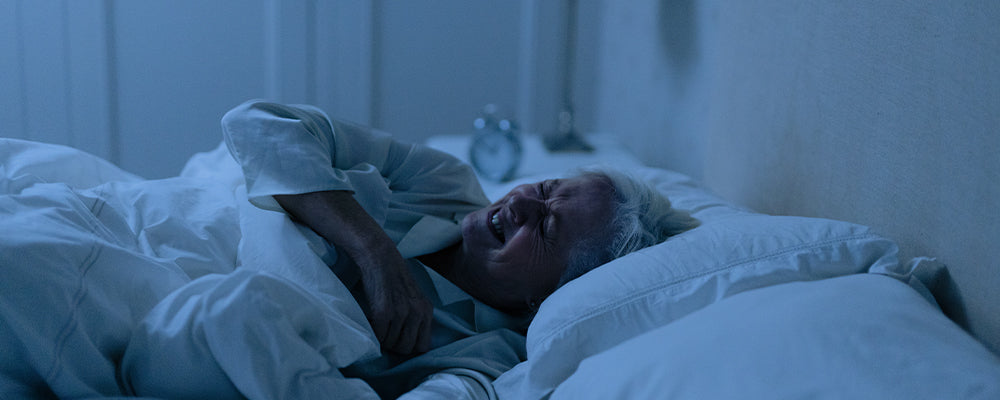 Older woman laid in bed looking uncomfortable