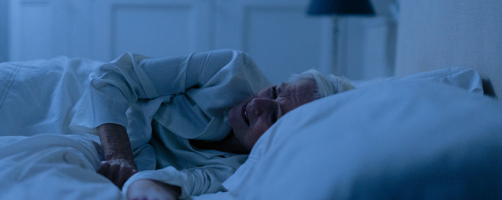 Older woman in bed that is uncomfortable and experiencing discomfort